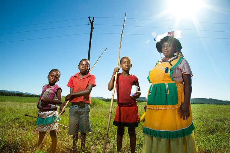 A family walk home in the harsh heat of the Waterberg region after collecting sticks to make innovative one-string guitars. Photo by by Thanda Kunene.