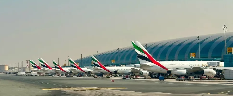 Dubai airport smoke plume, Dubai airport drone incident, DXB airport disruption, Emirates aircraft at Dubai airport, Dubai airport terminal passengers waiting, Dubai skyline smoke near airport, UAE airport security response, Middle East aviation disruption, Dubai International Airport runway activity, Getaway Magazine